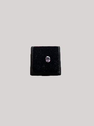 Small black box with a purplish gems held in a hand against a blurred background