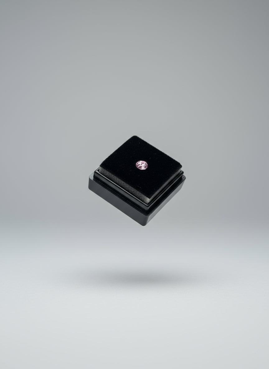 purplish stone over a Small black  box  held between fingers with a blurred background