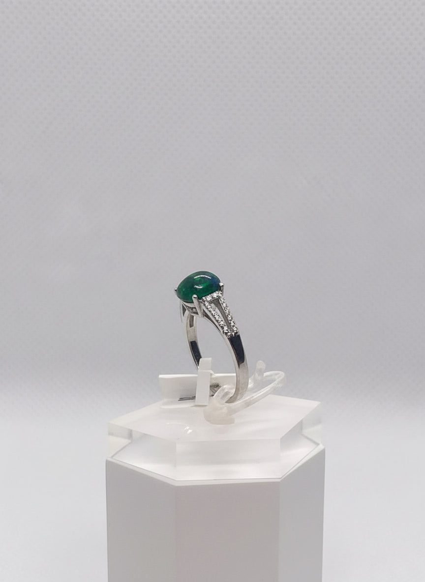 Silver ring with a opal greenish, reddish  and blueish gemstone held by a hand against a gray background