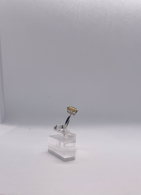 Close-up of a silver ring with a citrino gemstone  on a clear stand and white background