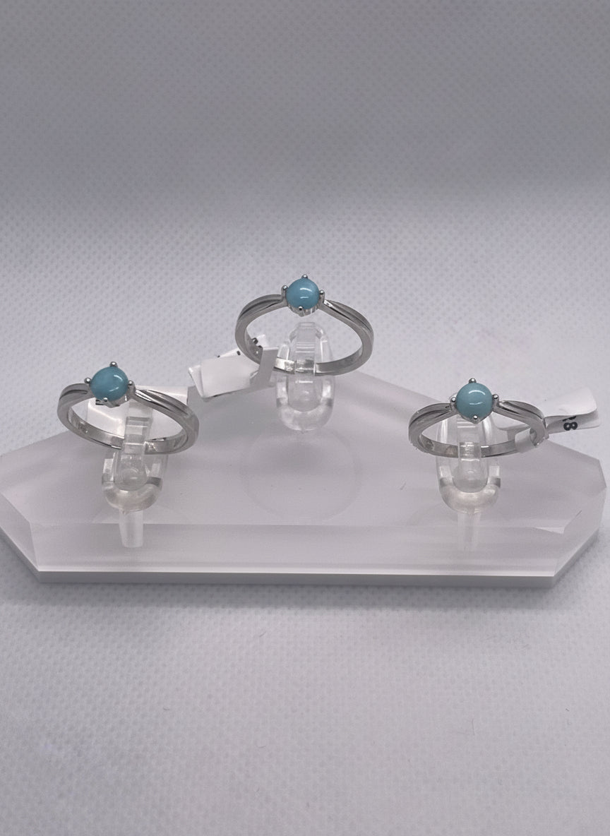 three rings  with blue gemstones on a clear stand  with a white background