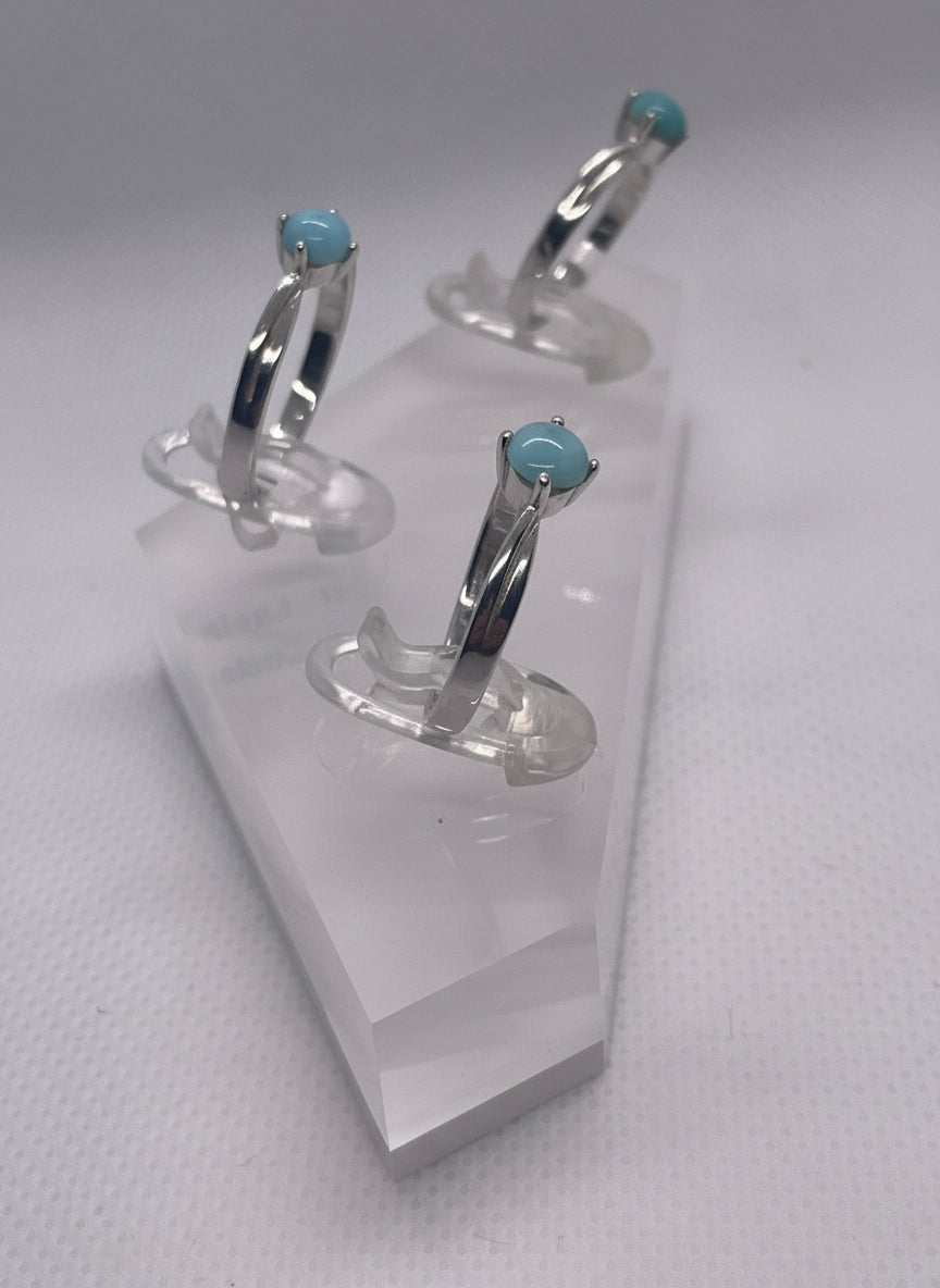 three rings  with blue gemstones on a holder with a white background