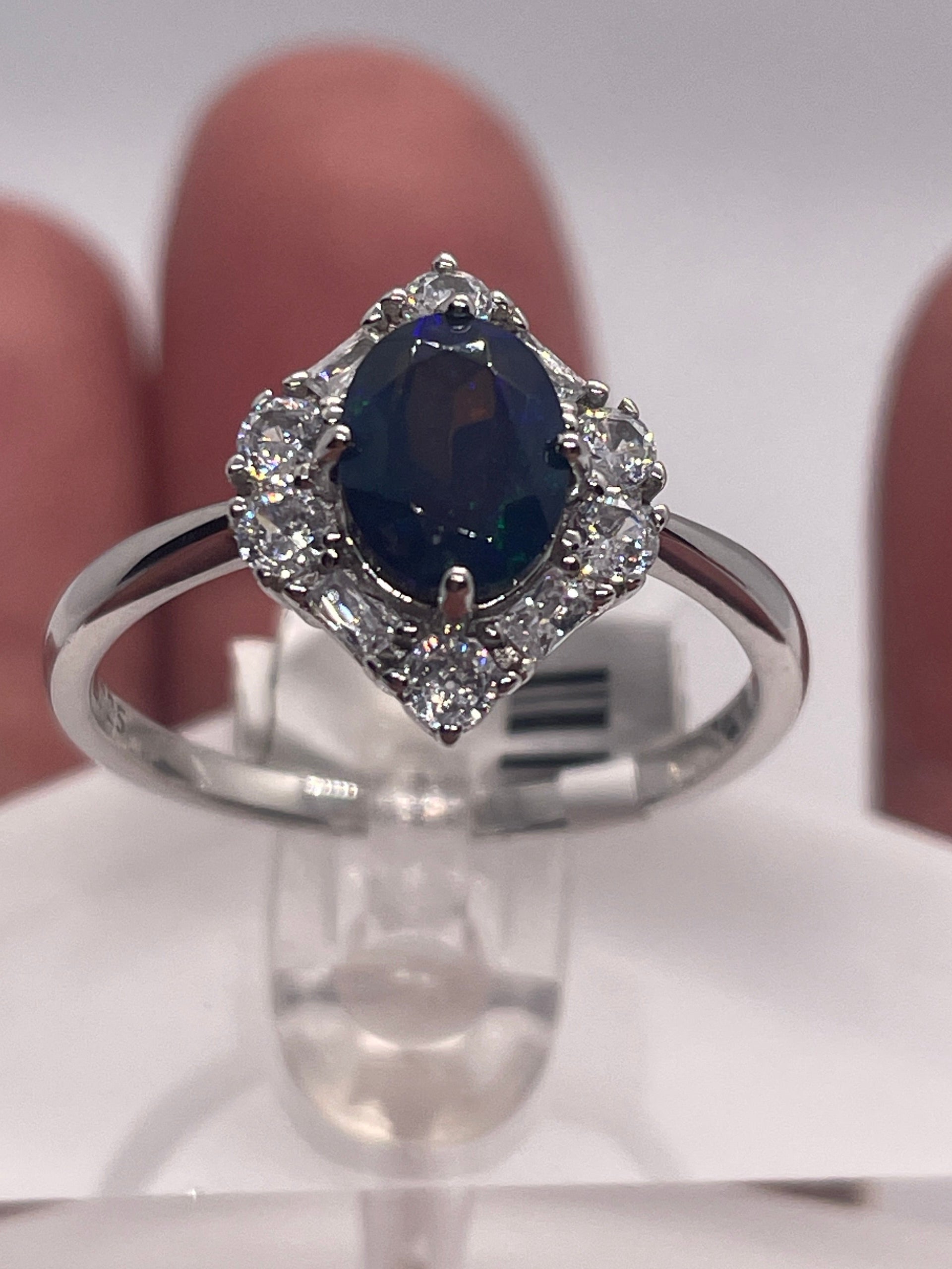 Silver ring with a blue gemstone on a white stand